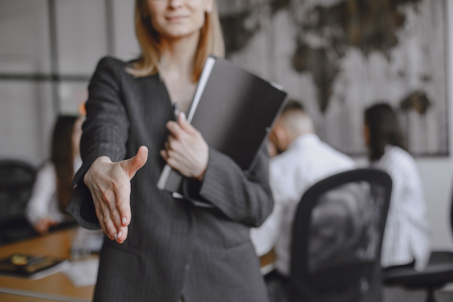 Woman in a suit holds a folder.